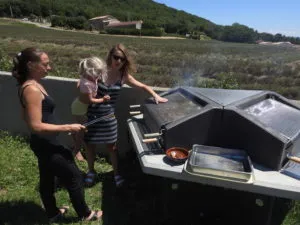 Barbecue collectif en utilisation Utilisatrices autour d’un barbecue collectif extérieur