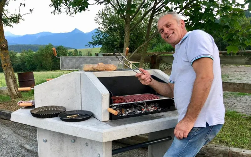 Utilisation du barbecue au gîte Vacancier préparant un repas sur le barbecue collectif d’un gîte